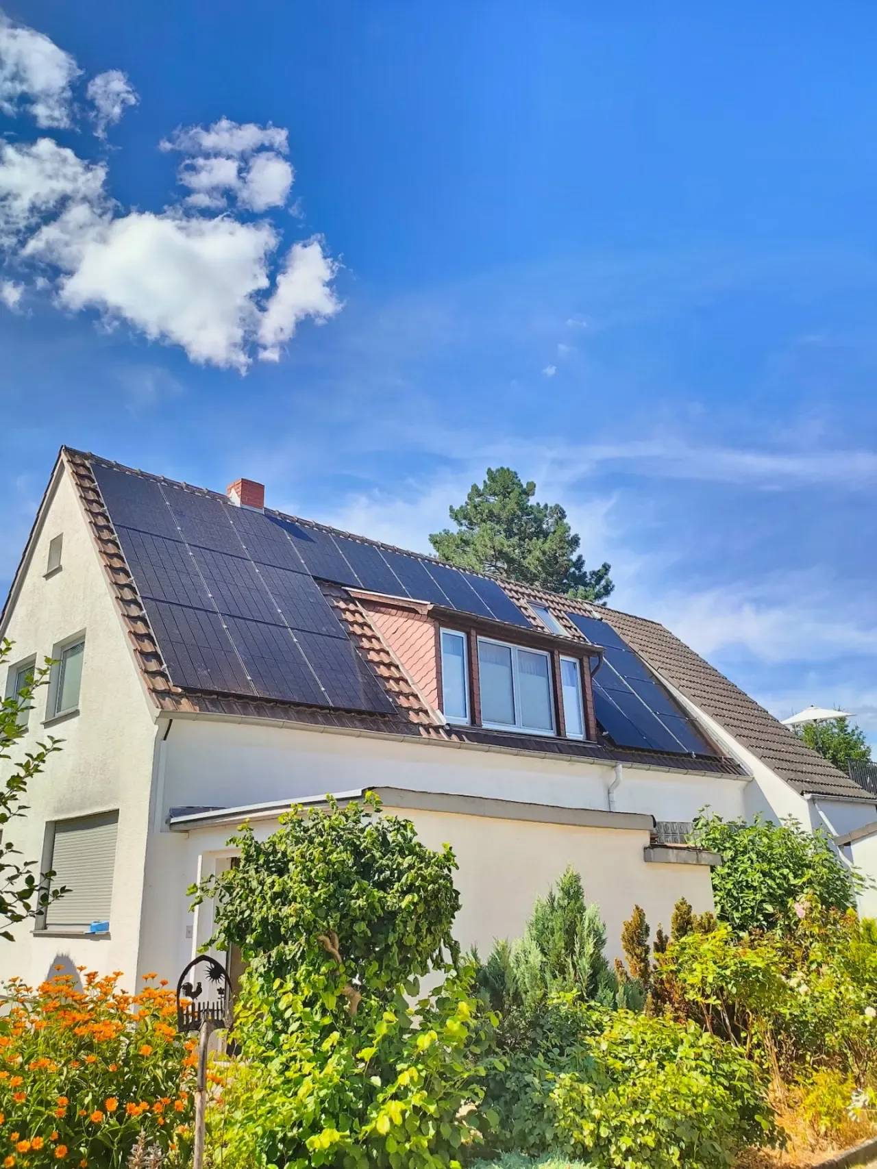 Photovoltaikanlage auf dem Dach eines Wohnhauses mit Garten